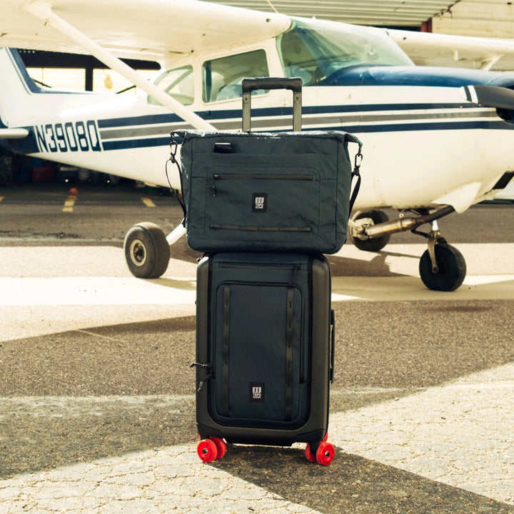 Topo Designs Global Pro Travel Roller with the Topo Designs Travel Tote on top in a travel setting